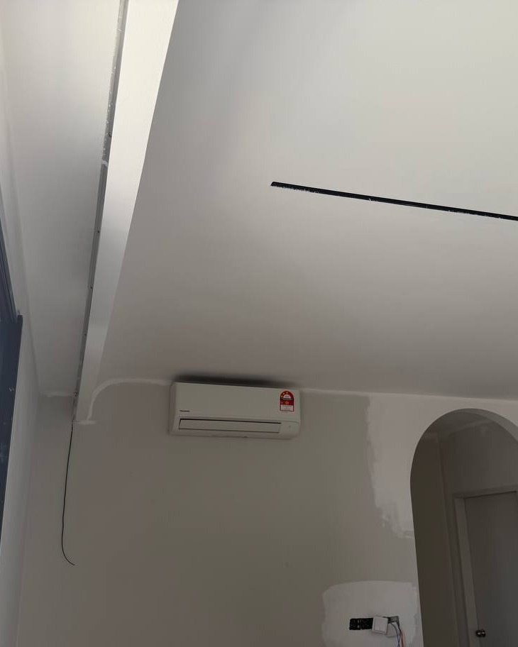 Curved Ceiling Drop with Concealed AC Unit – Bangsar Project Curved plaster ceiling drop with recessed cove edge above a wall-mounted Toshiba air conditioning unit in a Bangsar residential room, plain skim-coated finish ready for painting
