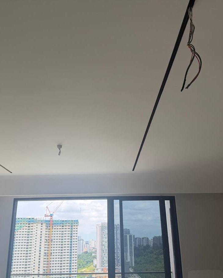 Recessed linear light channel groove in plaster ceiling with exposed electrical wiring awaiting connection, high-rise Bangsar condo unit with city skyline view