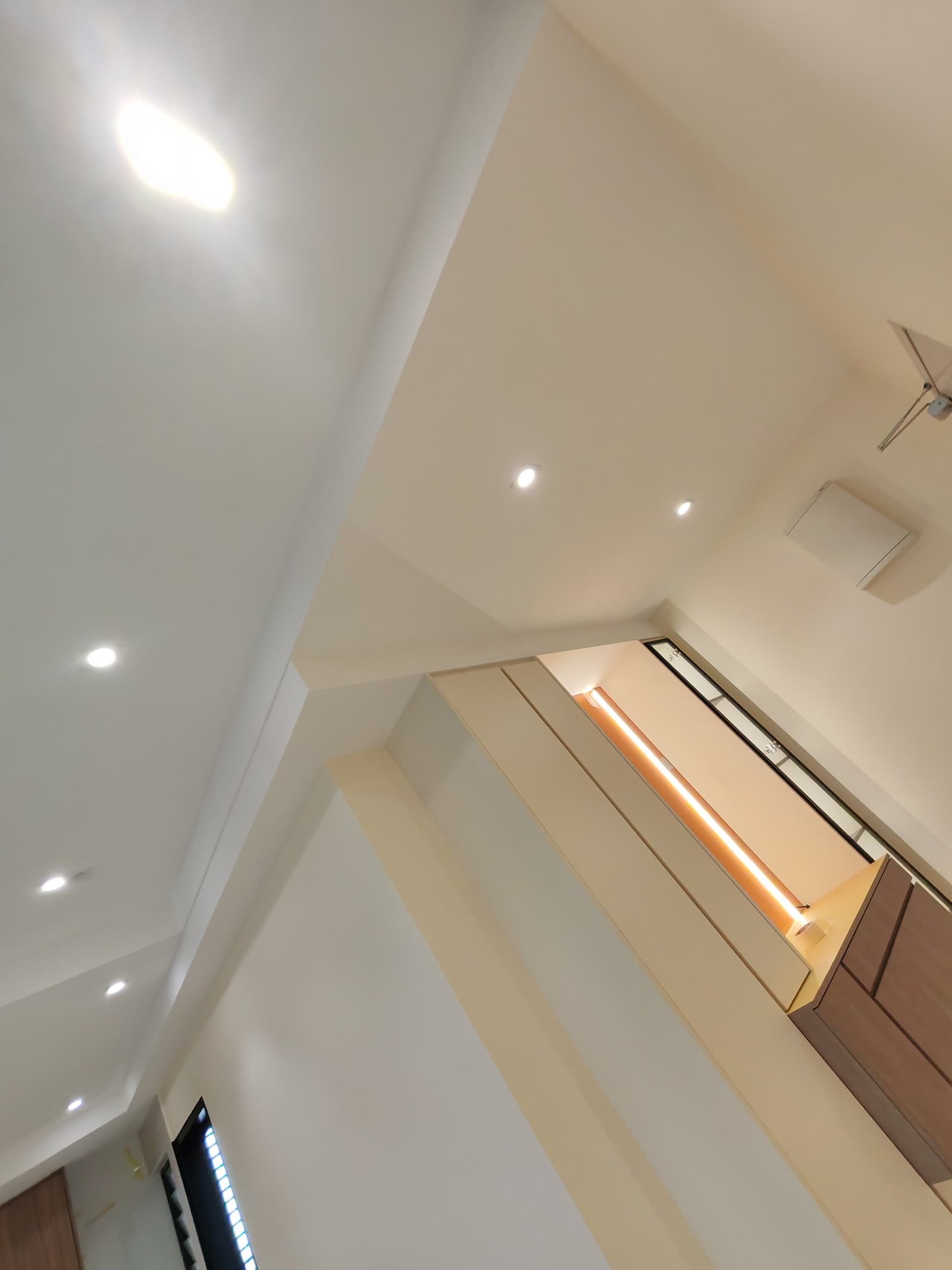 Ceiling Downlights to Amber-Lit Console Nook Plaster ceiling with recessed downlights leading to a hallway console nook lit by warm amber LED strip lighting, Sungai Long home renovation