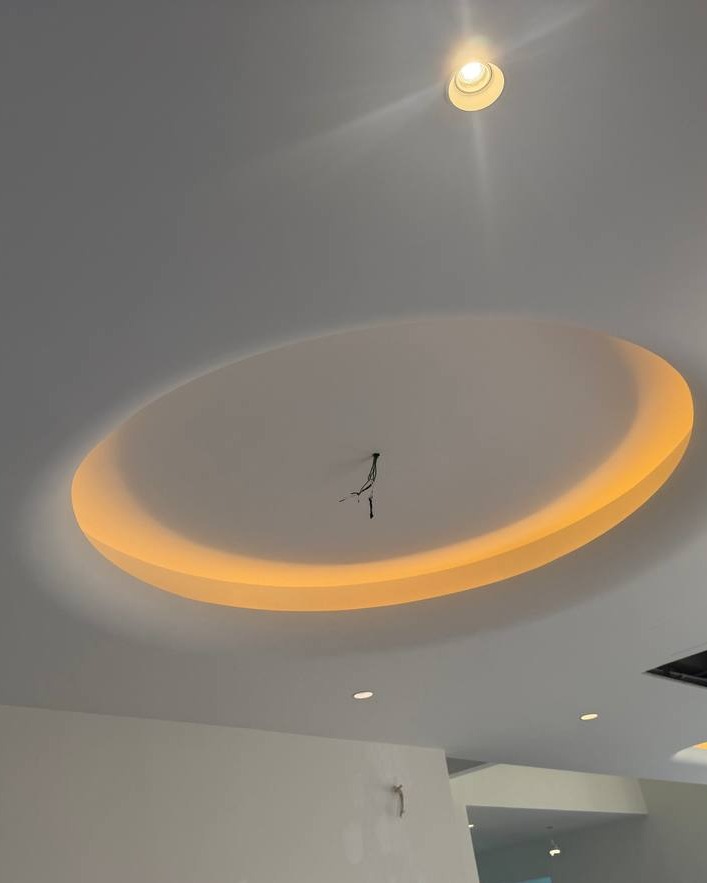 Oval recessed plaster ceiling cove with warm LED light trough and exposed pendant wiring, Klang residence circular light trough ceiling design