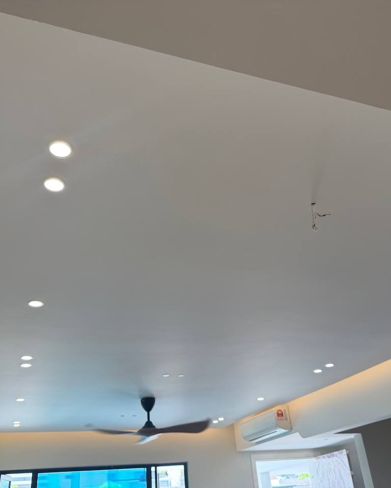 Multi-level plaster ceiling with curved cove lighting edge, recessed downlights, exposed wiring point for ceiling fan, and wall-mounted air conditioner unit in Rawang residential ground floor renovation
