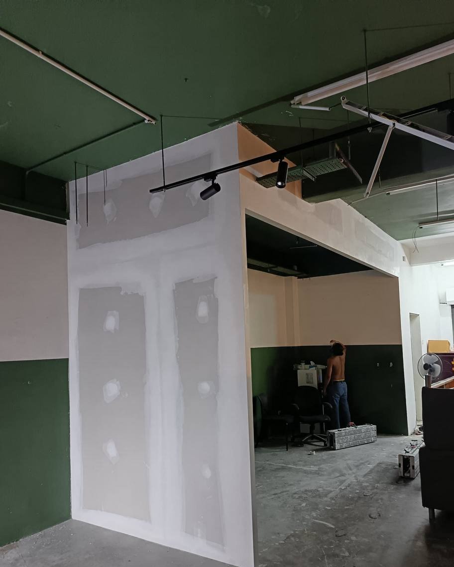 Skim-coated drywall partition wall with plaster-filled screw joints forming an office entrance opening, installed under a green ceiling in Shah Alam office fit-out project
