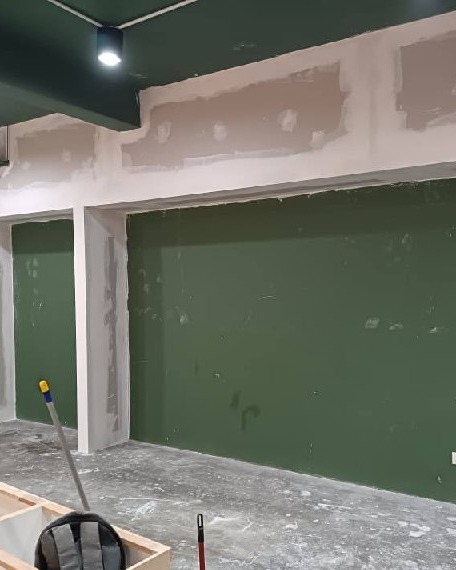 Shah Alam Office Partition Wall - Plastered Cornice Detail Green-painted partition wall with white plastered ceiling cornice and stud column, mid-construction office fit-out in Shah Alam
