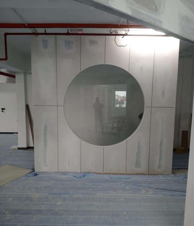Drywall partition screen with a large round clear-glass window during construction, Shah Alam renovation